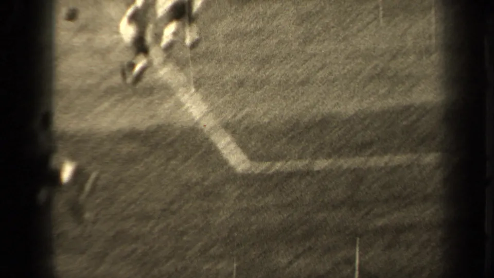 1947 Paris 8mm frame with blurred football play near a white field line, showing partial figures and strong film grain.