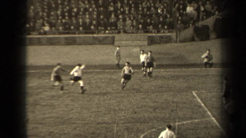 Men in soccer uniforms run across a Paris stadium pitch in 1947, filmed from a high spectator position.
