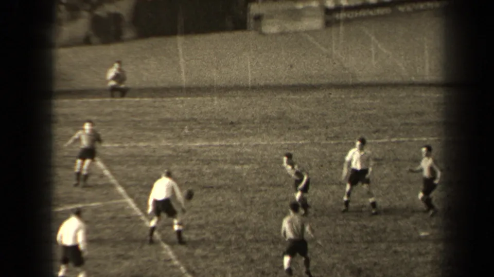 Wide 8mm view of a 1947 Paris soccer match, with players spaced around the ball on a marked grass field.