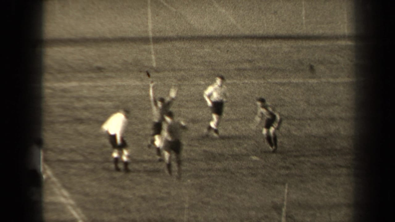 1947 Paris home-movie frame showing soccer players in light and dark kits converging as the ball rises near a player.