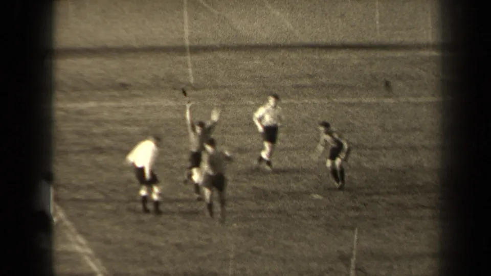 1947 Paris home-movie frame showing soccer players in light and dark kits converging as the ball rises near a player.