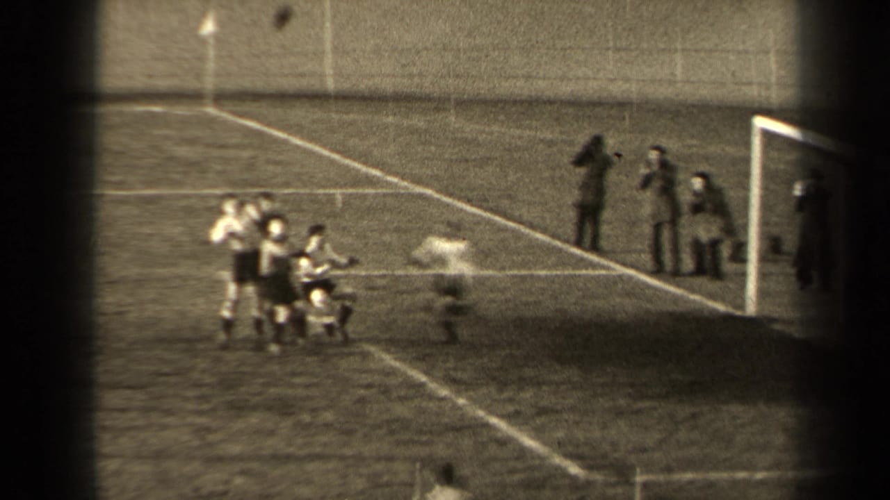 1947 Paris home-movie frame showing young men near a soccer goal as spectators stand along the field edge.