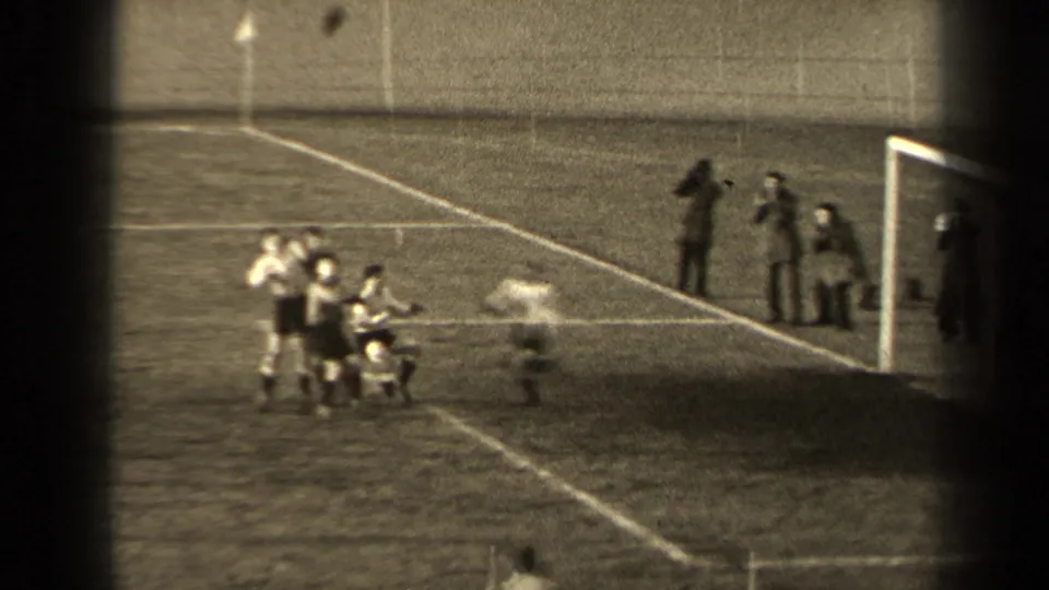 1947 Paris home-movie frame showing young men near a soccer goal as spectators stand along the field edge.