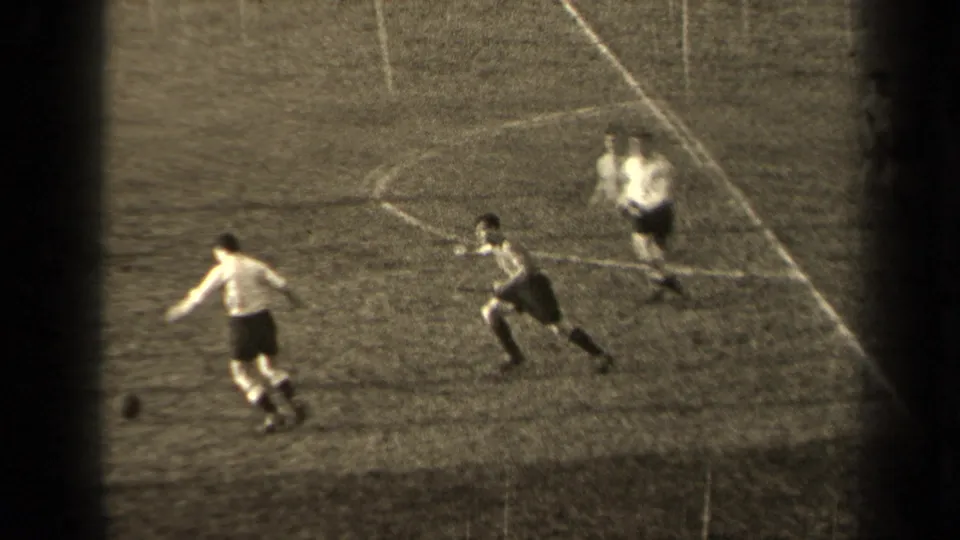 1947 Paris home-movie frame showing two young men in soccer kit chasing the ball across the pitch.