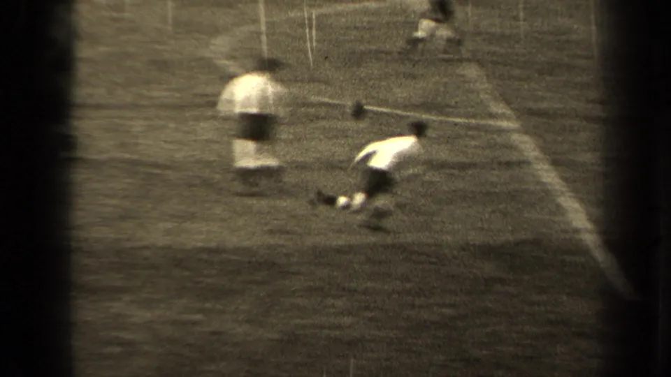 Near the goal area in the 1947 Paris football footage, one player appears to reach or fall toward the ball as others watch nearby.