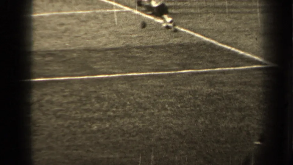 Several soccer players appear near a diagonal white line on the 1947 Paris field, with motion blur from the 8mm footage.