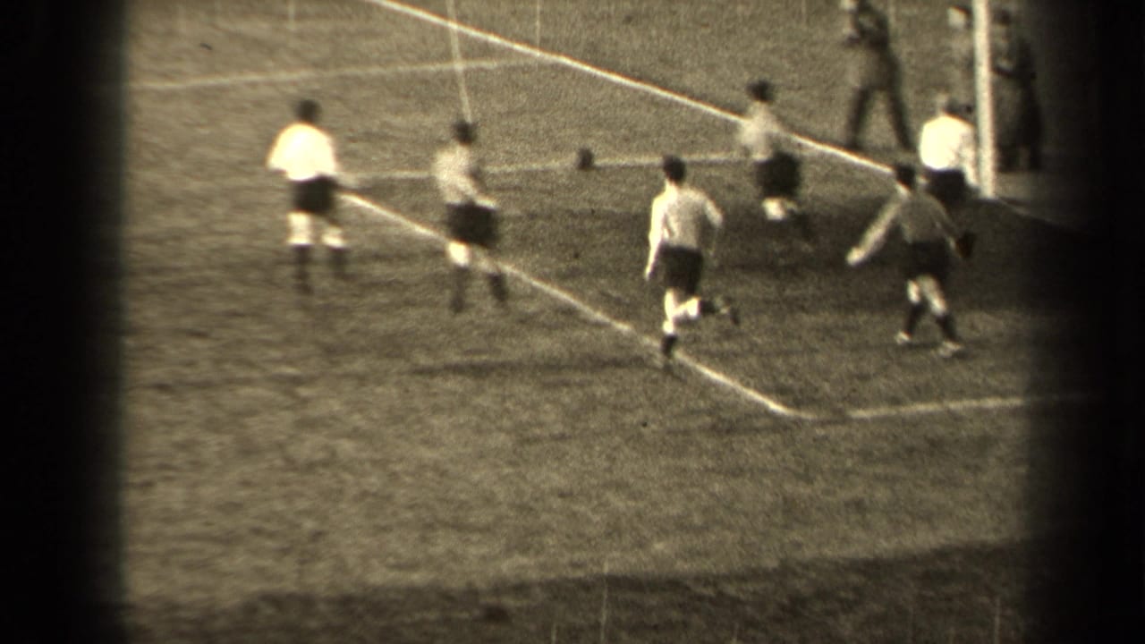 1947 Paris home-movie frame showing football players in light shirts and dark shorts near the edge of a grass pitch.