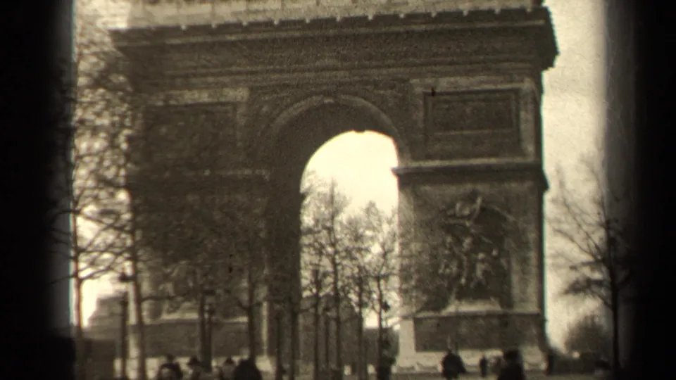 1947 Paris frame showing the Arc de Triomphe, tree silhouettes, sculptural detail, and pedestrians in the foreground.