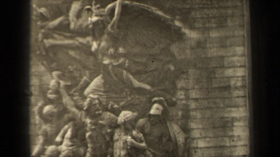 1947 Paris home-movie frame showing the central winged sculpture more clearly above clustered relief figures and a masonry background.