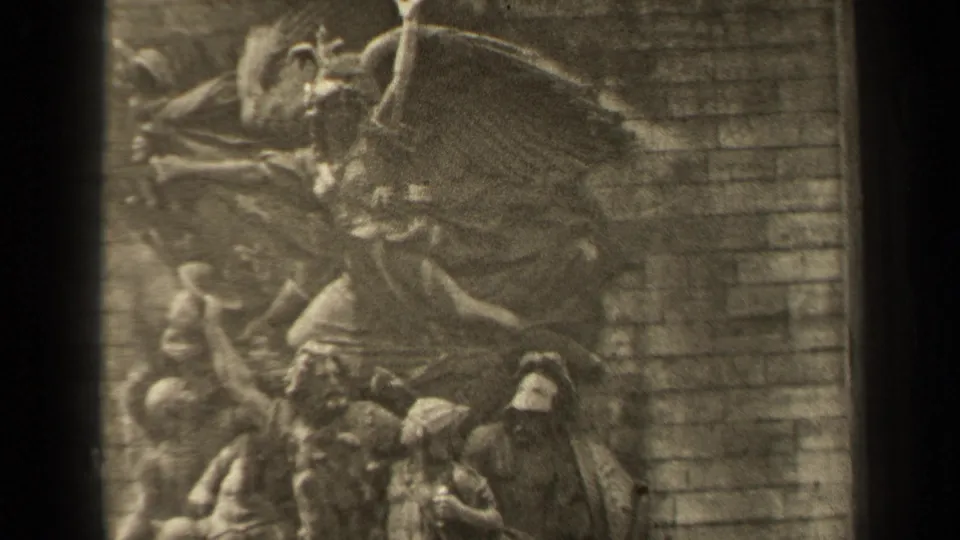 Final 1947 Paris frame shows the monument relief with a winged central figure, lower carved forms, and the adjoining stone block wall.