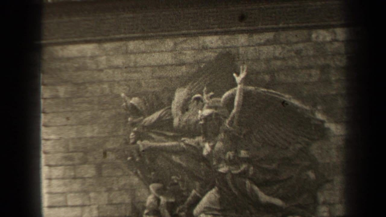 1947 Paris 8mm frame showing a stone bas-relief with a winged central figure, smaller carved human forms, brickwork, and dark film borders.