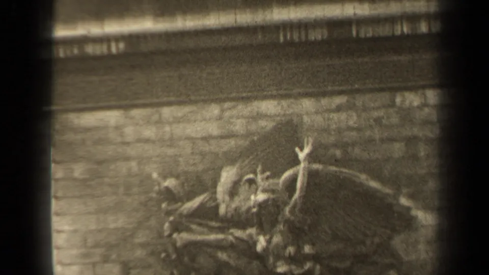 1947 Paris 8mm frame of the relief from a slightly shifted angle, showing the winged figure, raised arm, brick backing, and stone trim.