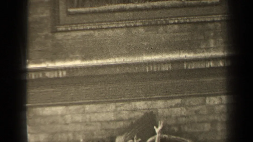 1947 Paris 8mm frame with the camera drifting downward, showing stone trim, brickwork, dark borders, and a partial view of the relief.