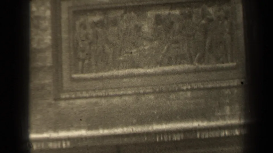 1947 Paris 8mm frame showing a rectangular carved stone panel beneath the relief area, with brickwork, molding, and heavy film grain.