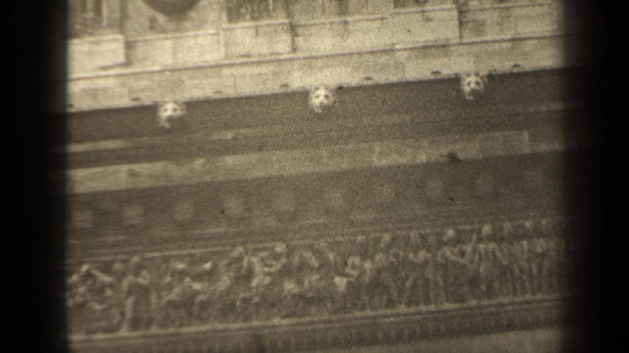 Stone building facade with relief carving, medallions, and shadowed bands.