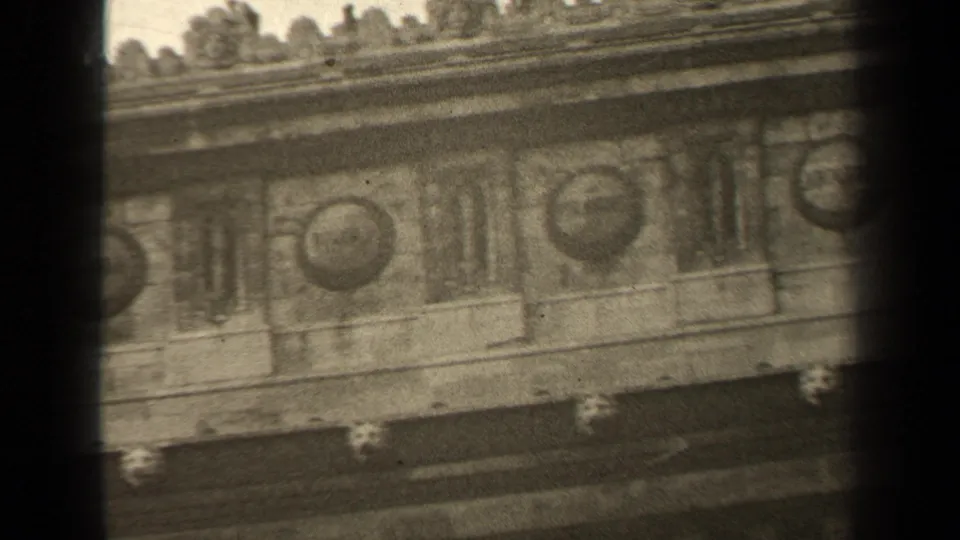 1947 Paris 8mm frame capturing repeated stone medallions and carved facade panels under uneven home-movie exposure.