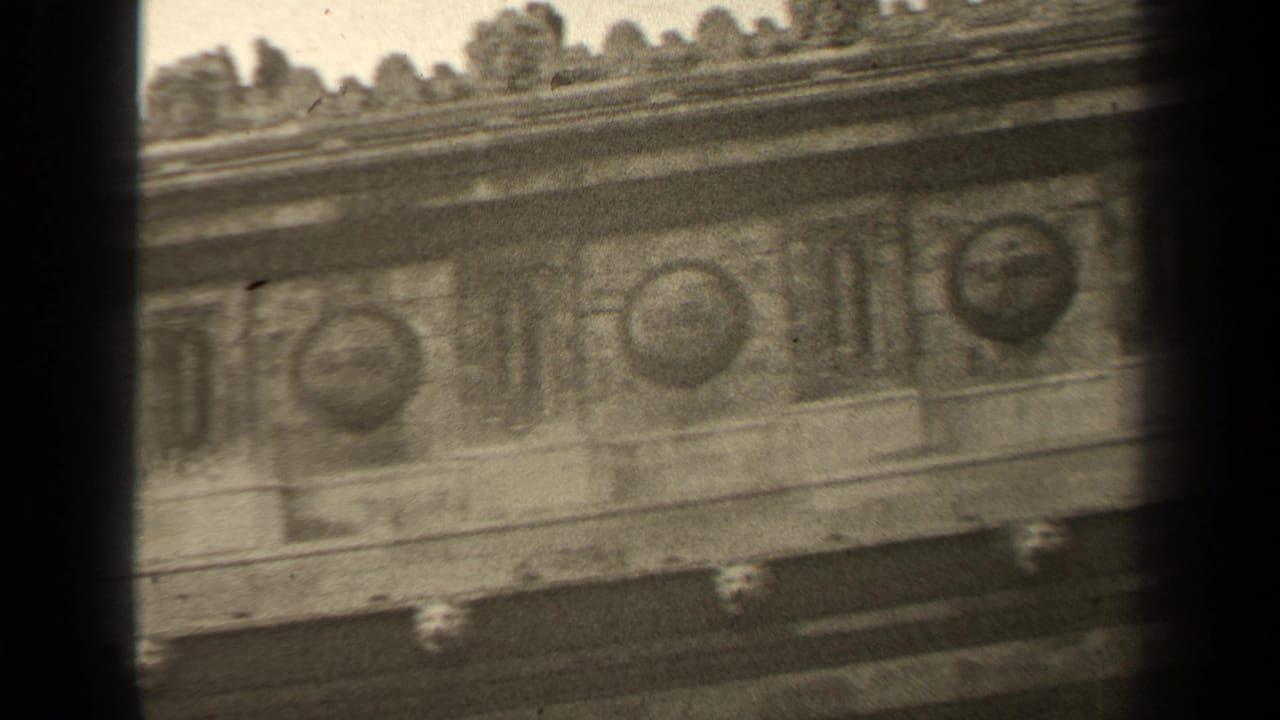 1947 Paris 8mm frame showing an angled close-up of an ornate stone frieze with circular medallions and decorative cornice detail.