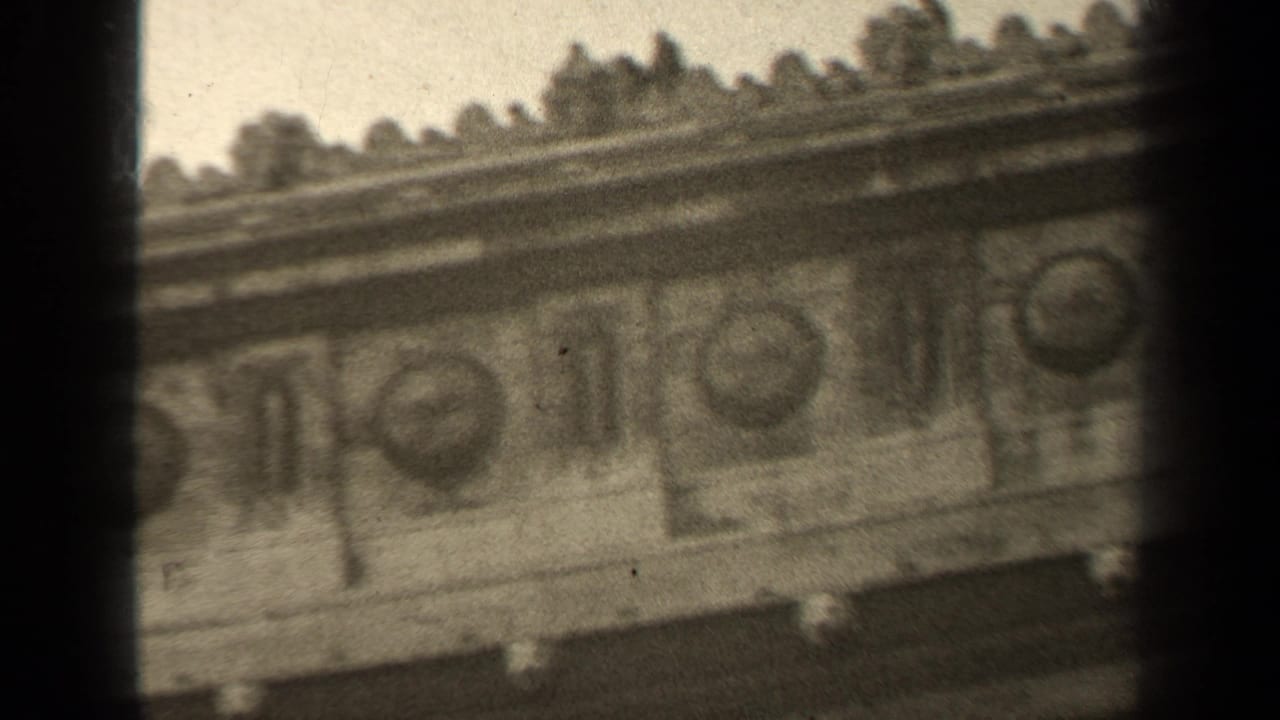 Ornate stone facade detail with repeated round medallions and dark frame edge.