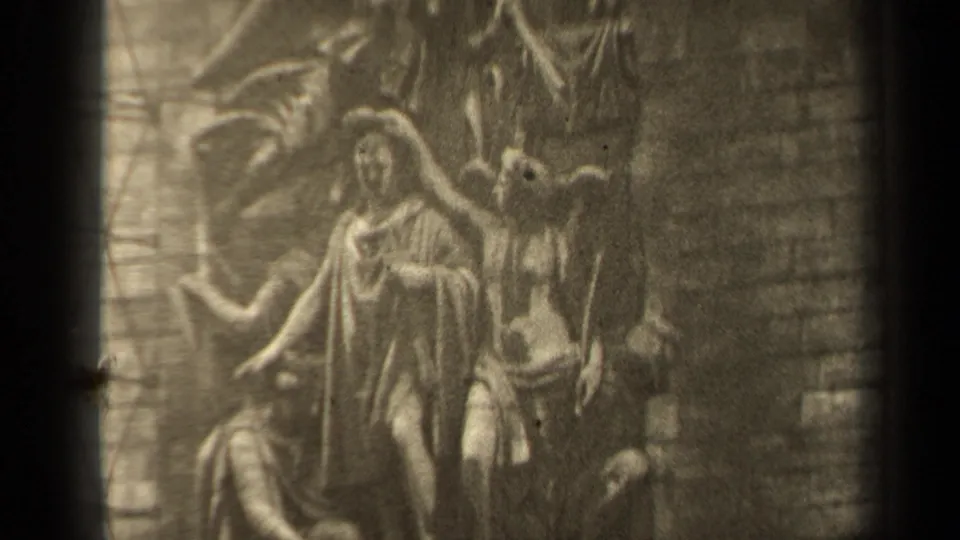 1947 Paris frame with a closer view of a religious stone relief, showing robed figures and angel-like forms against brick.