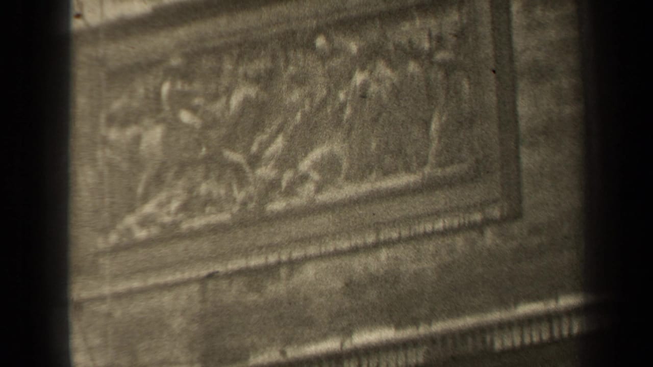 1947 Paris 8mm frame showing ornate carved stone panels and masonry details, partly blocked by dark vertical edges.