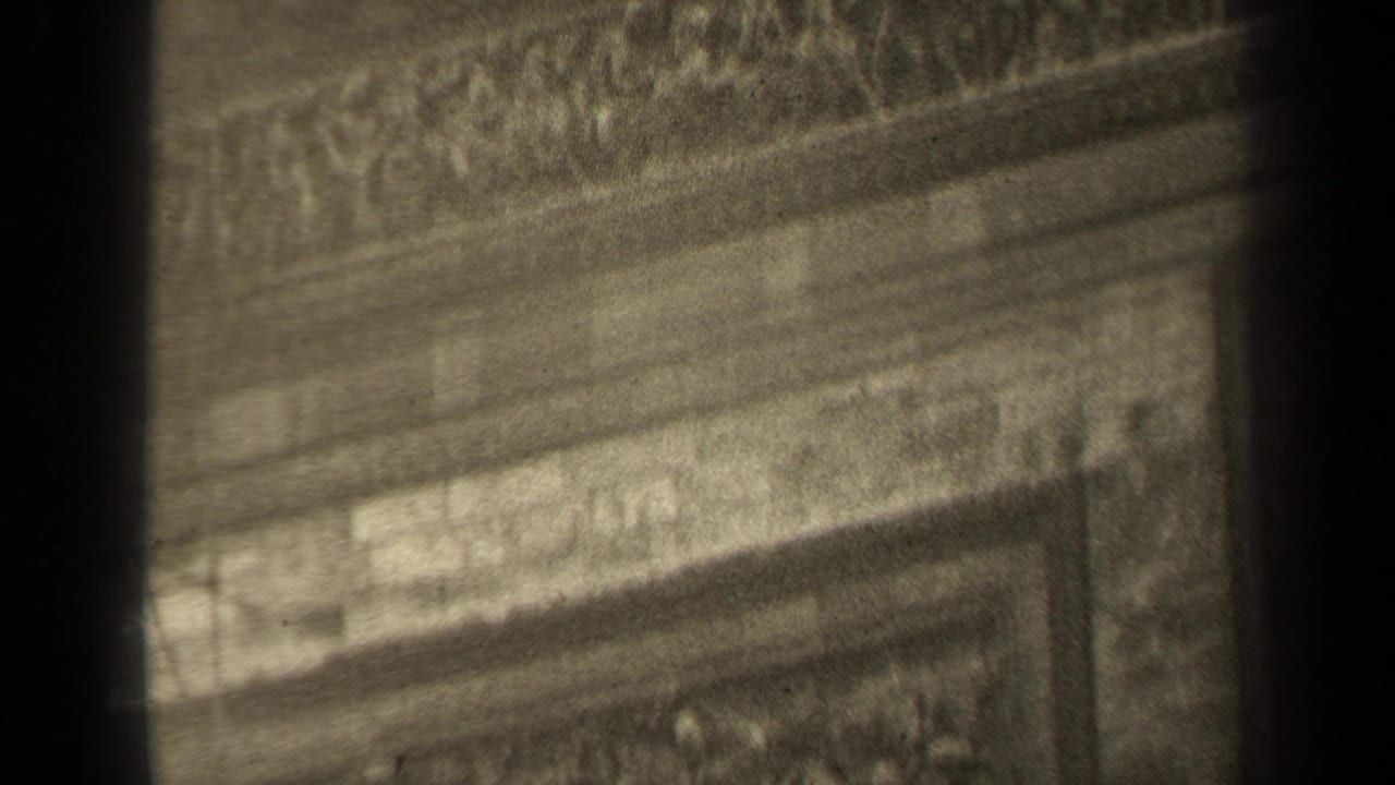 Decorated stone facade with relief bands and a dark vertical obstruction through the center.