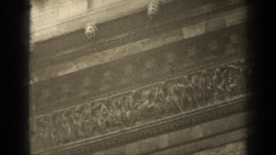 Close 1947 Paris view of carved stone bands and small sculptural forms on a historic facade, filmed with soft 8mm grain.