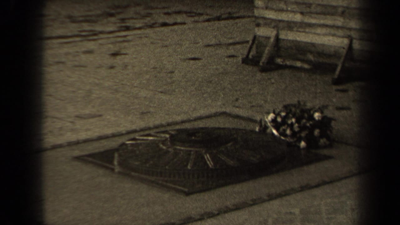 1947 Paris 8mm frame showing a low memorial flame or marker in stone paving with a bouquet placed to one side.