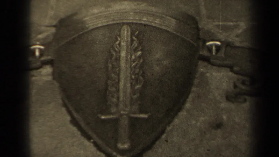 1947 Paris memorial detail with a sword-and-flame shield emblem seen in soft, grainy 8mm footage.