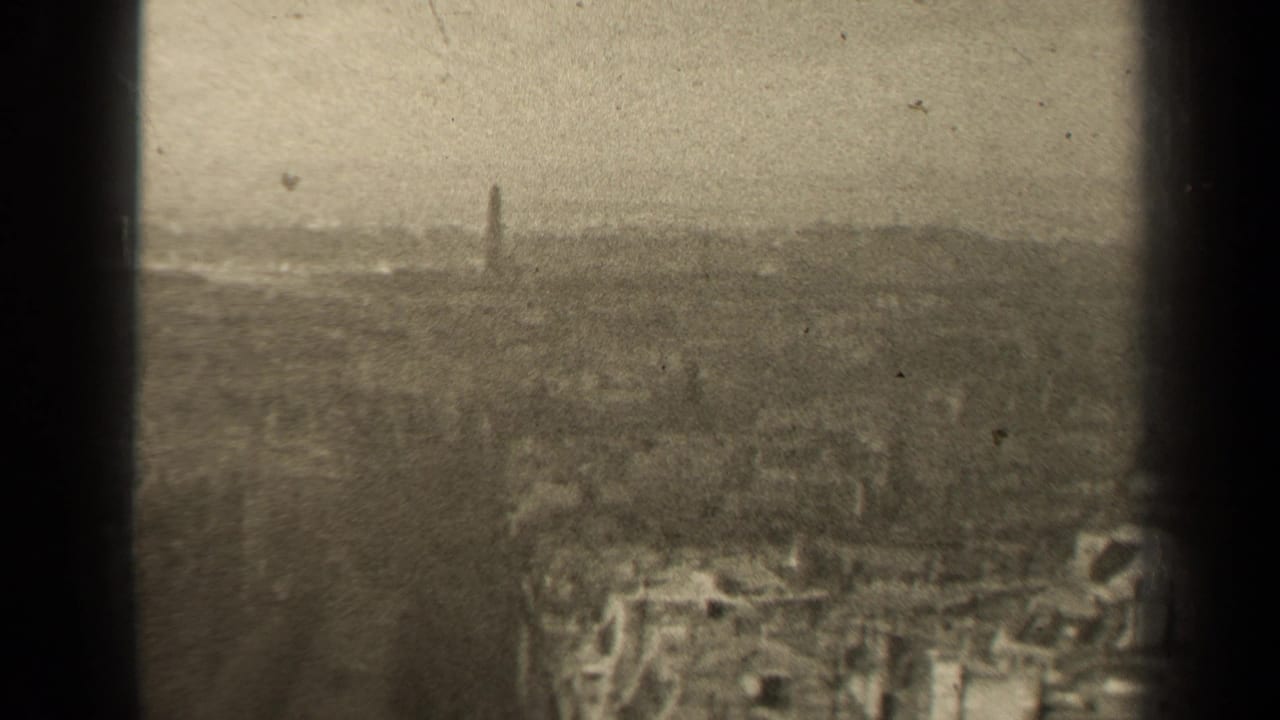 1947 Paris home-movie frame showing a soft, hazy skyline with dense rooftops and a narrow tower in the distance.
