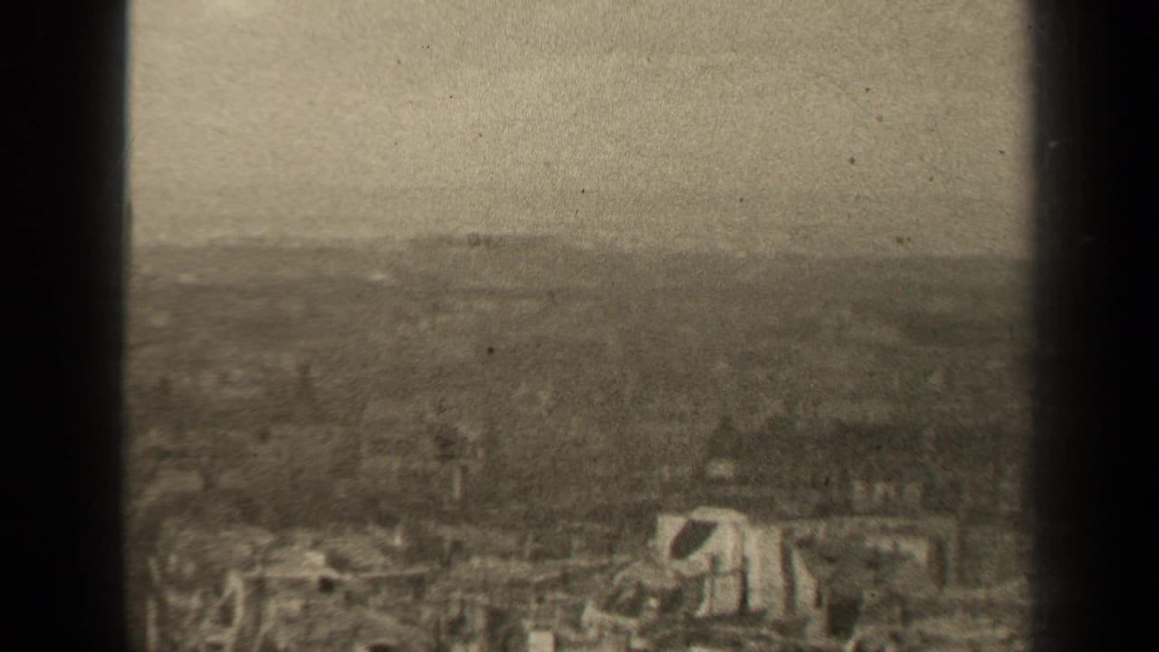 1947 Paris metadata view of a damaged urban area, with collapsed structures, debris, and a soft hazy skyline in grainy 8mm footage.