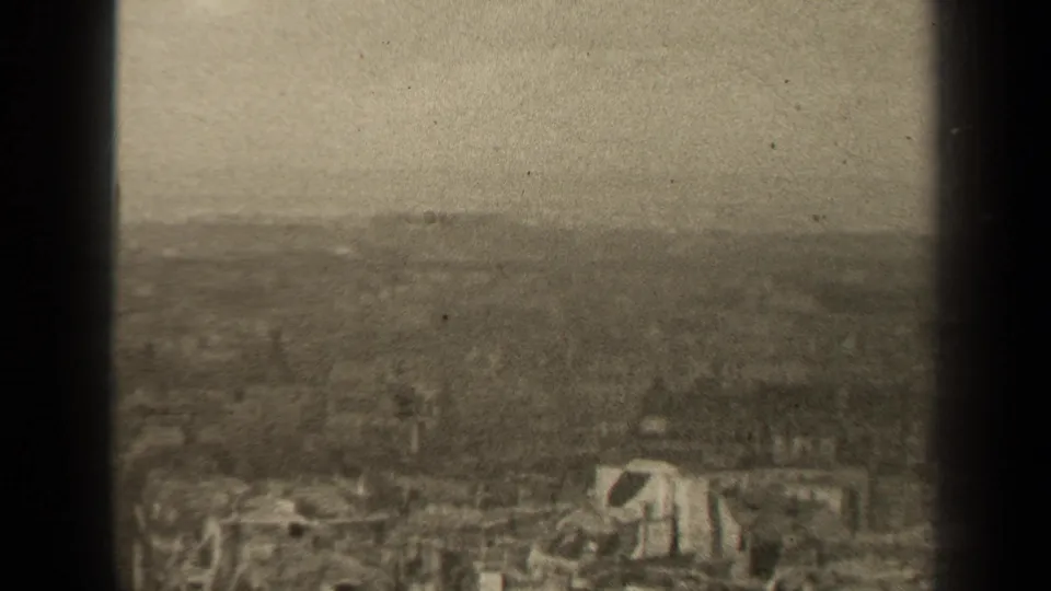 1947 Paris metadata view of a damaged urban area, with collapsed structures, debris, and a soft hazy skyline in grainy 8mm footage.