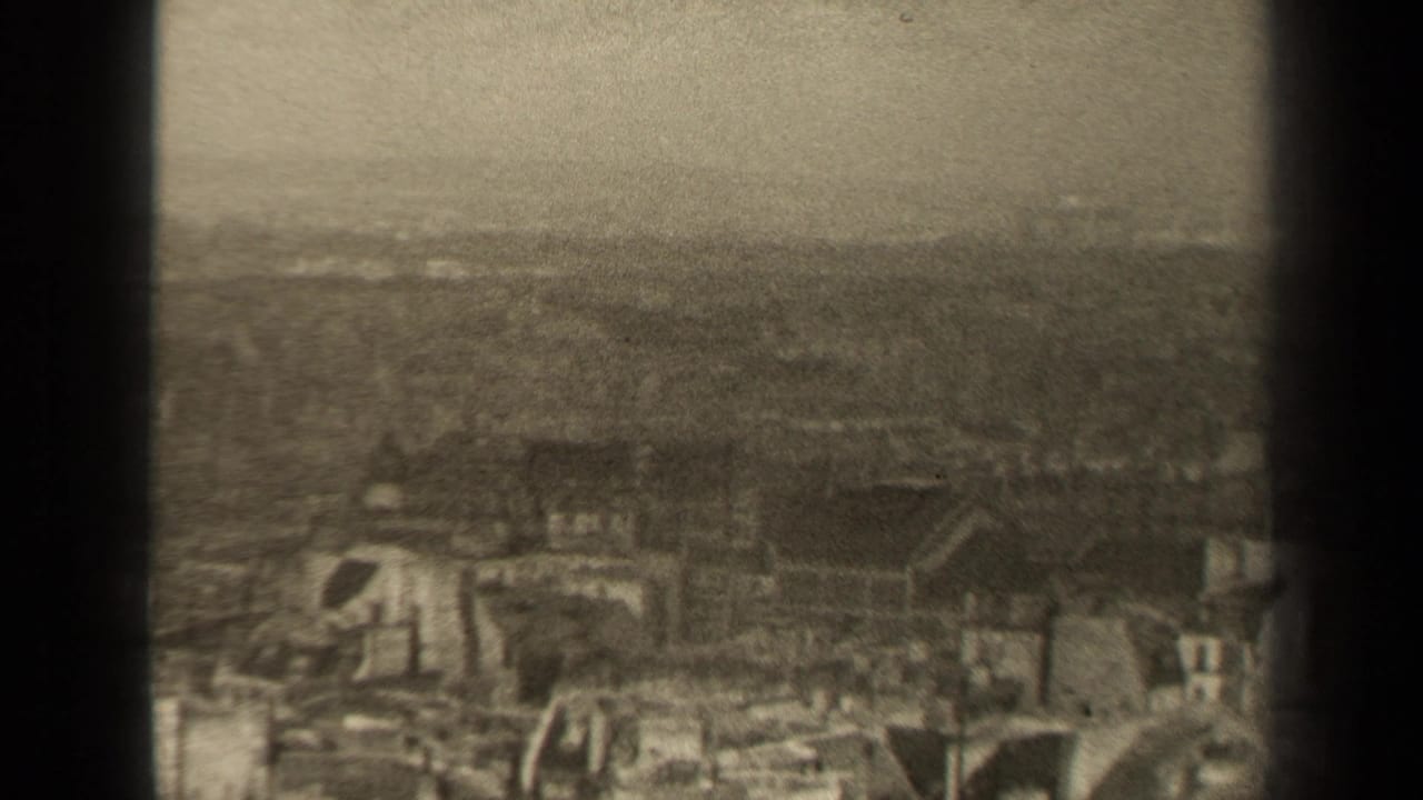 1947 Paris home-movie frame showing a hazy elevated view over dense rooftops and a muted horizon.