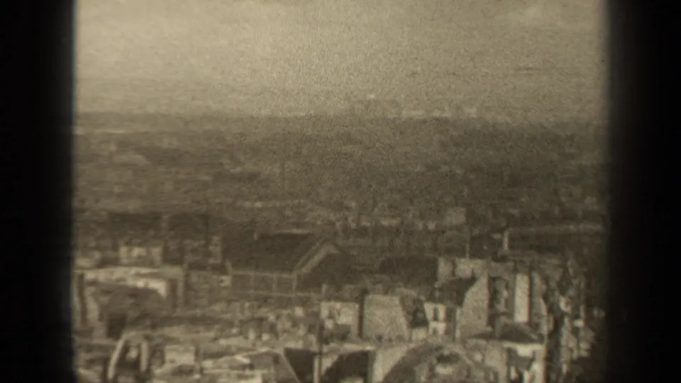 1947 Paris home-movie still showing dense rooftops and an obscured skyline in sepia-toned haze.