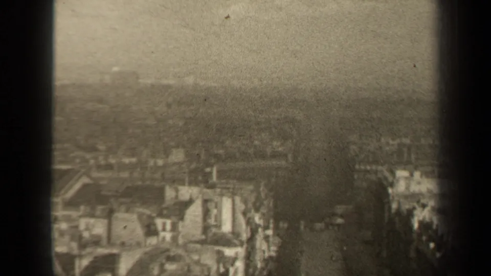 1947 8mm high-angle view over Paris rooftops and streets, with distant horizon and soft overcast exposure.