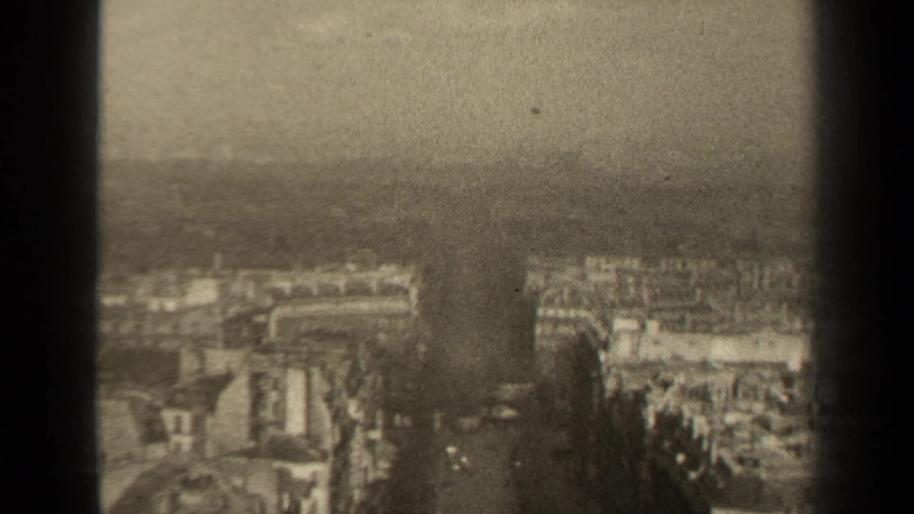 High-angle 1947 Paris view showing apartment blocks, street corridors, haze, and the edge of the 8mm frame.