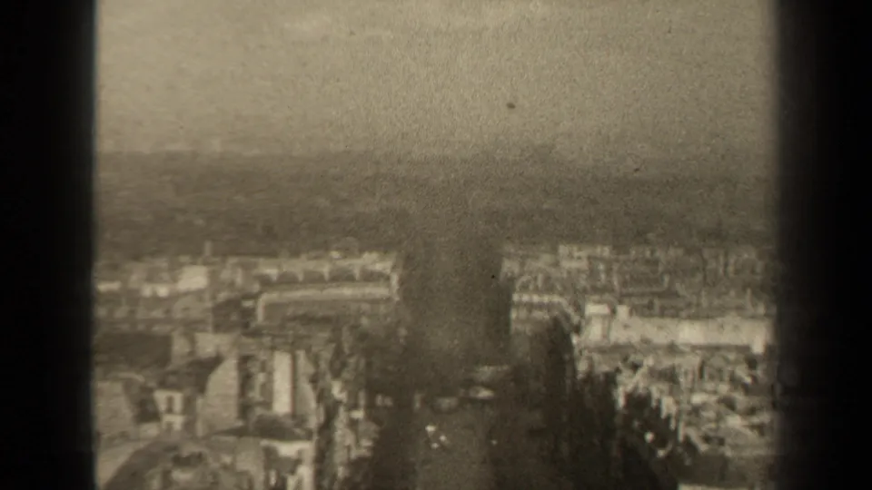 High-angle 1947 Paris view showing apartment blocks, street corridors, haze, and the edge of the 8mm frame.