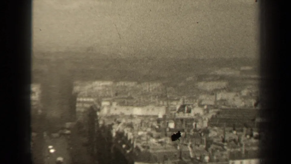 Final 1947 Paris frame showing rooftops and streets from above, softened by haze, grain, and a visible film mark.
