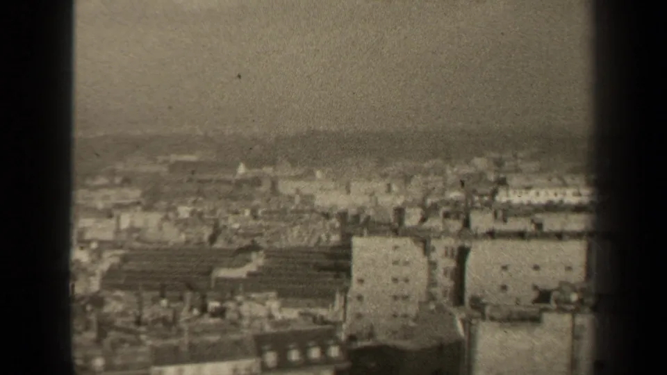 Final 1947 Paris frame showing a hazy rooftop panorama, pale block buildings, and dark vertical film-edge framing from the 8mm scan.