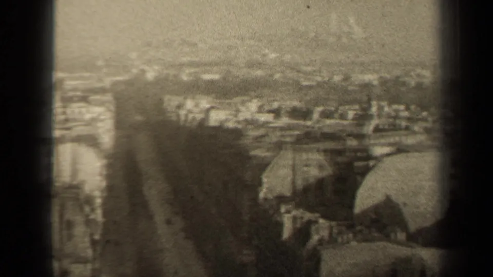 Sepia 1947 Paris panorama with a street corridor, distant rooftops, and rounded foreground roof forms.