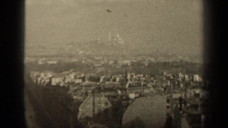 Final 1947 Paris frame holds on the elevated cityscape, with clustered buildings, a faint skyline, visible grain, and black frame borders.
