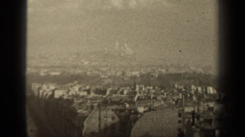 1947 Paris city panorama with dense rooftops and distant hills, partly framed by dark window-like edges.