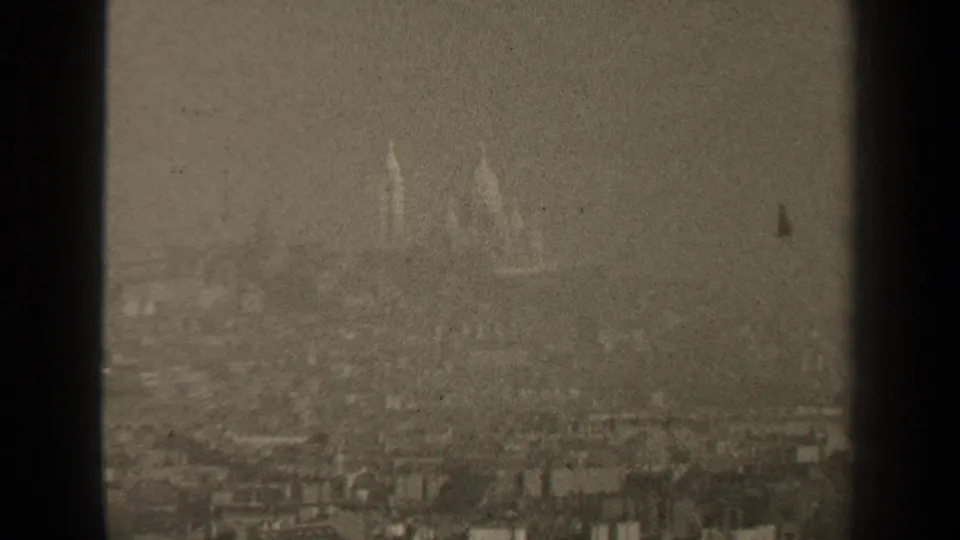 1947 Paris home-movie frame with domes and spires faintly visible above a hazy urban foreground.