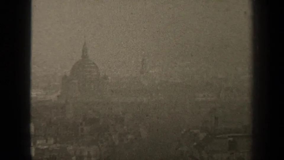 1947 Paris home-movie frame showing a distant domed landmark through haze and dark window bars.