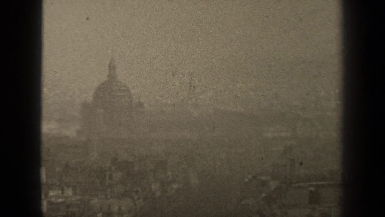 Distant domed landmark and rooftops partly obscured by haze and window framing.