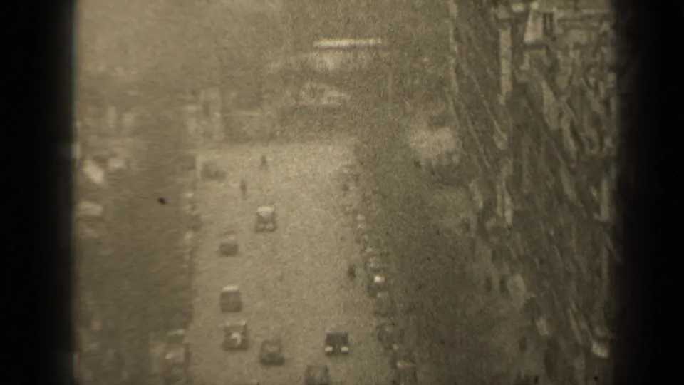 Elevated 1947 Paris street scene with cars below, small pedestrian figures, and tall buildings lining the roadway.