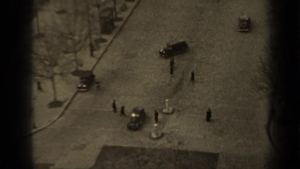 Elevated 1947 Paris street scene showing pedestrians crossing near vintage cars, bare trees, and a curved curb line.