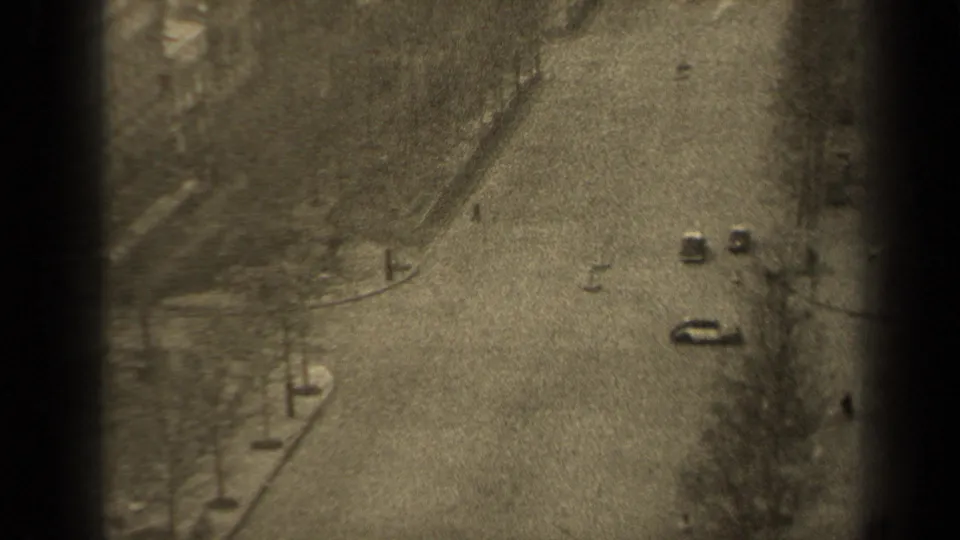 High-angle 1947 Paris street view with cars traveling along a broad road bordered by bare trees and sidewalks.