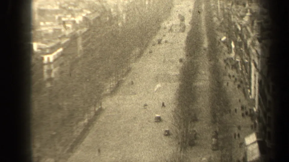 High-angle 1947 Paris street view with sparse automobiles, pedestrians, dense building rows, and heavy 8mm grain.