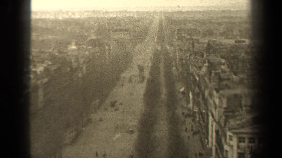 1947 Paris home-movie view looking down a broad street from above, with bare trees, buildings, and soft sepia exposure.