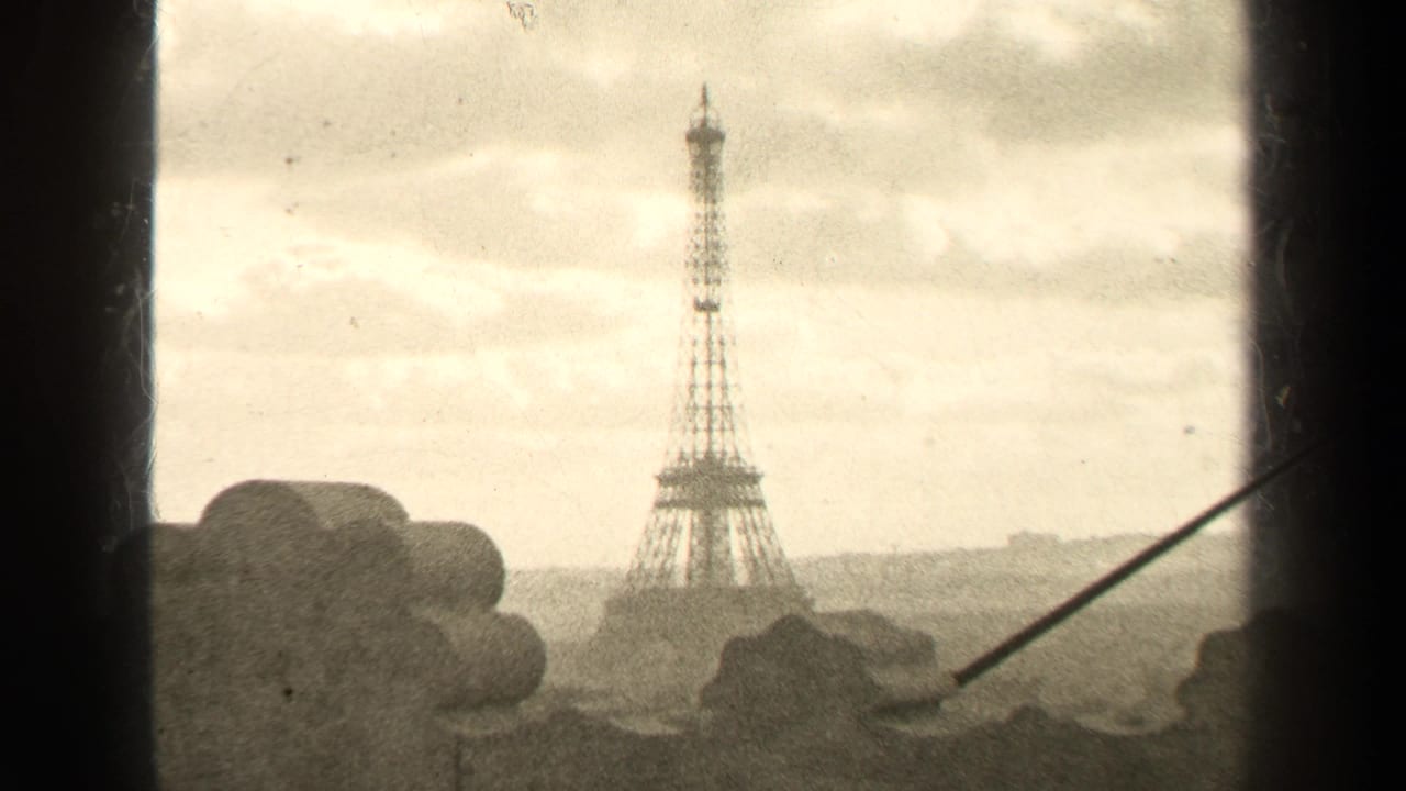 Distant Eiffel Tower seen through dark window edges with stonework in the foreground.